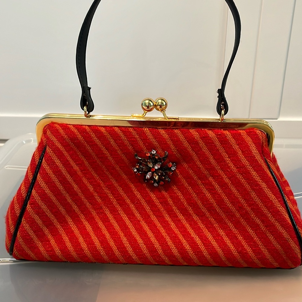 Glenda Gies red handbag with brooch.